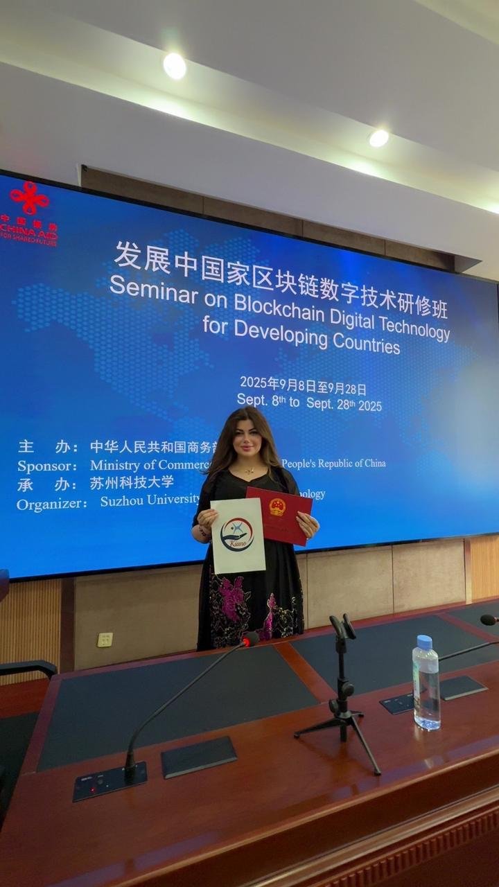 Standing before the seminar programme screen holding a certificate and the KIANO logo