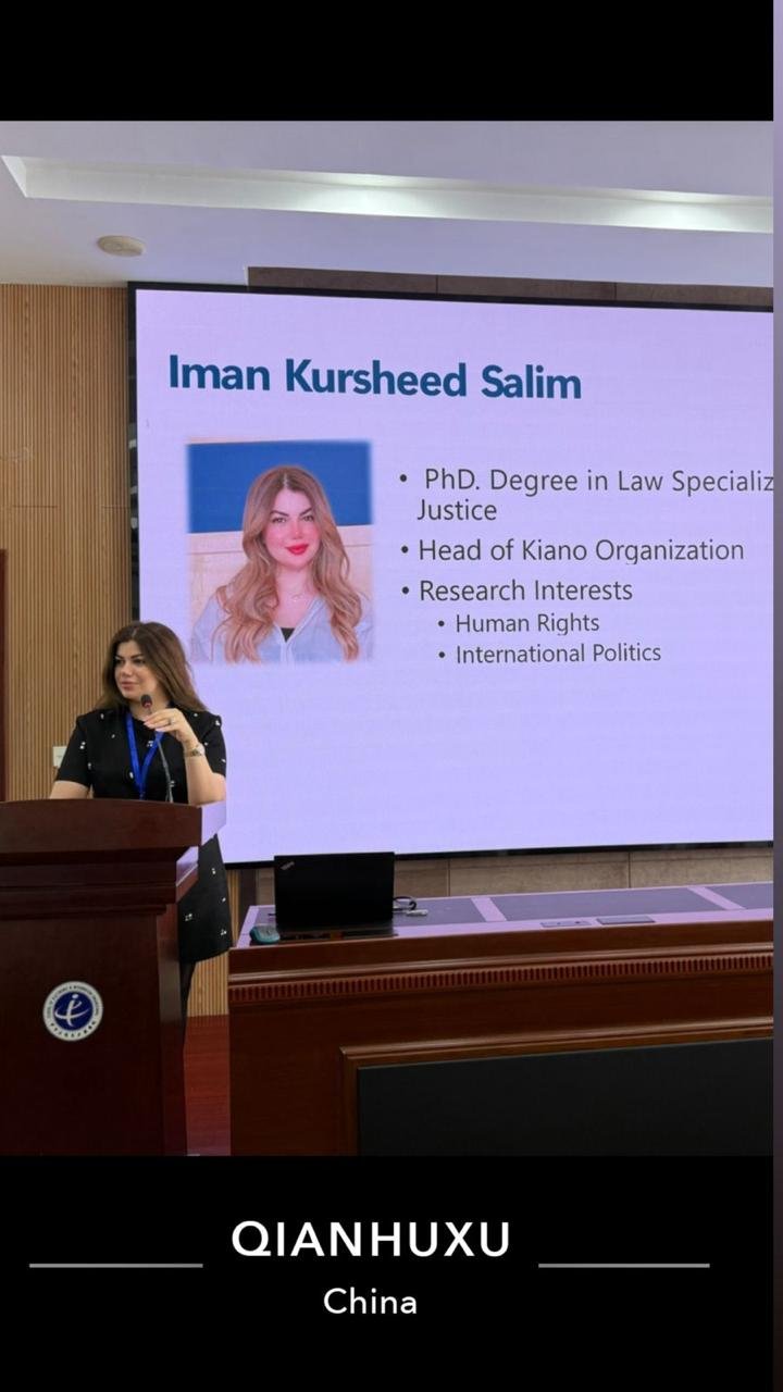 KIANO's head presenting from a lectern at the seminar in China, with an introductory slide on screen