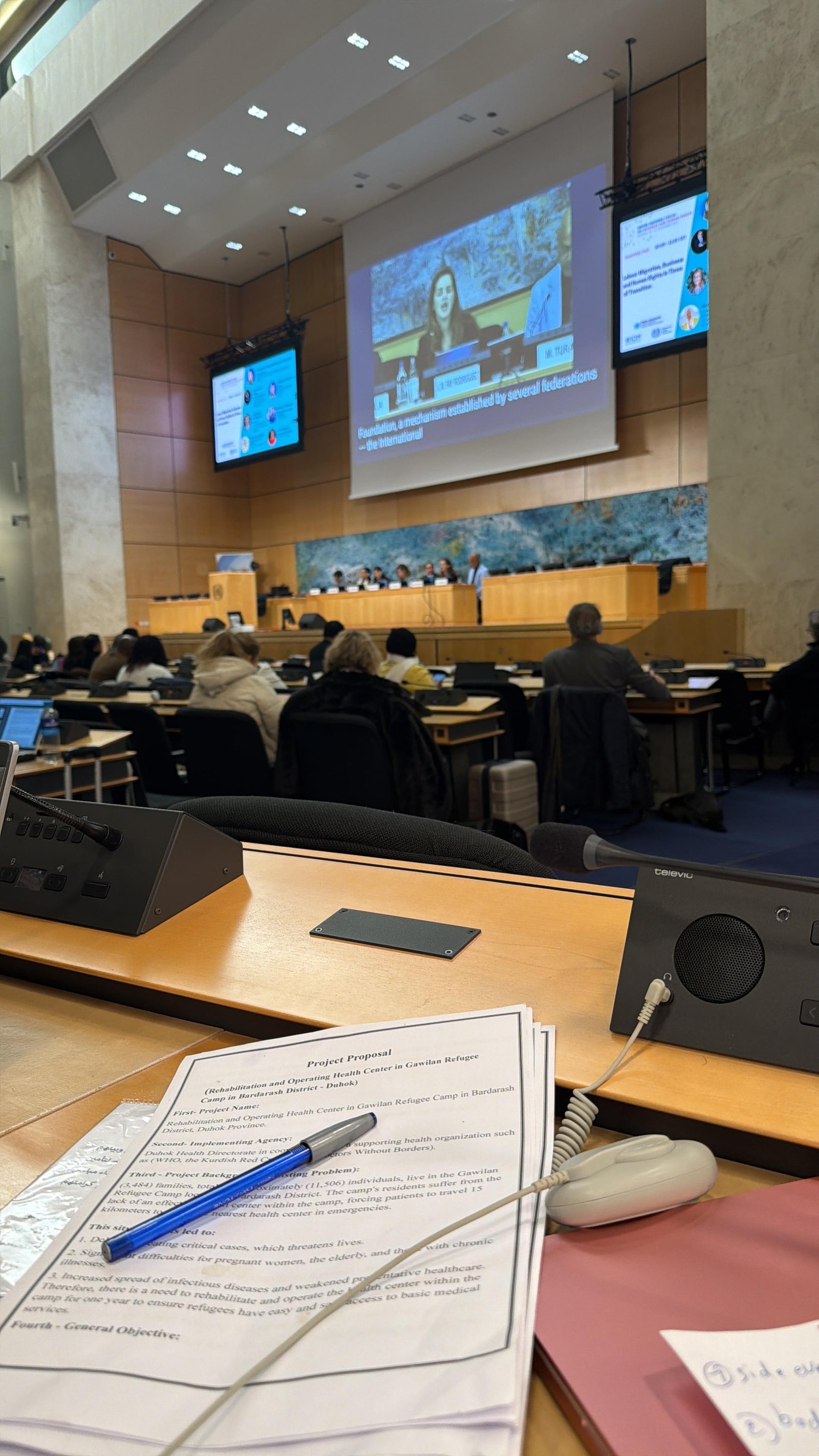A KIANO project proposal for rehabilitating the health centre in Gawilan Refugee Camp on a desk in a Geneva conference room