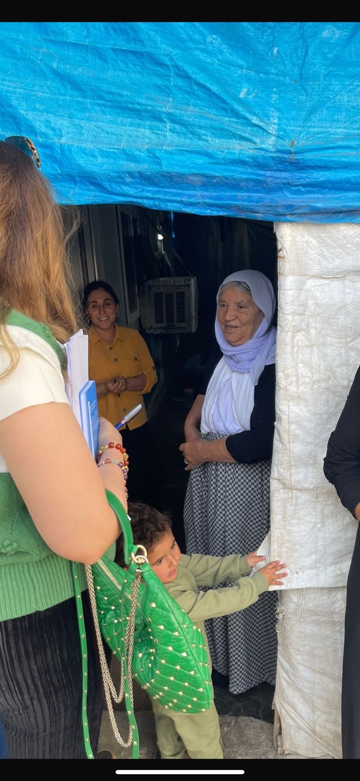 A KIANO team member speaking with an elderly woman at the entrance to her shelter