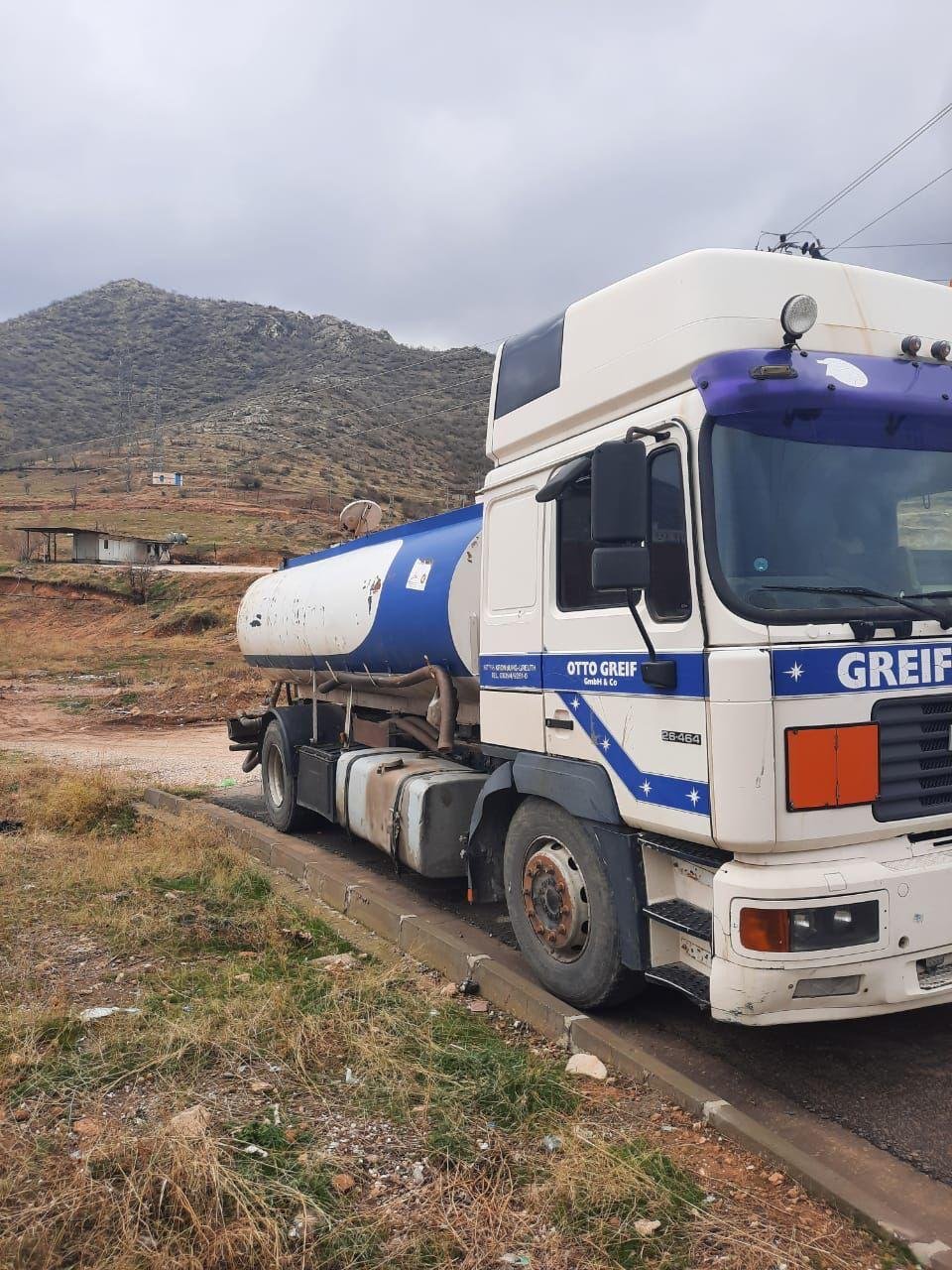 A water tanker truck parked on a rural road delivering clean water